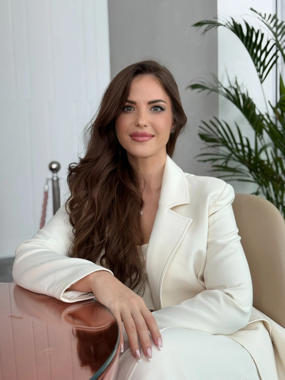 Marina, founder of treatmehome, seated in a cream jacket
