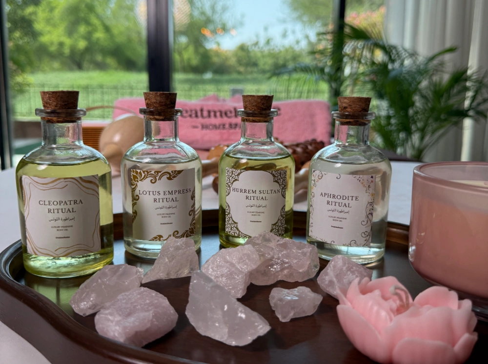 Four treatmehome ritual oils beside rose quartz and a pink candle