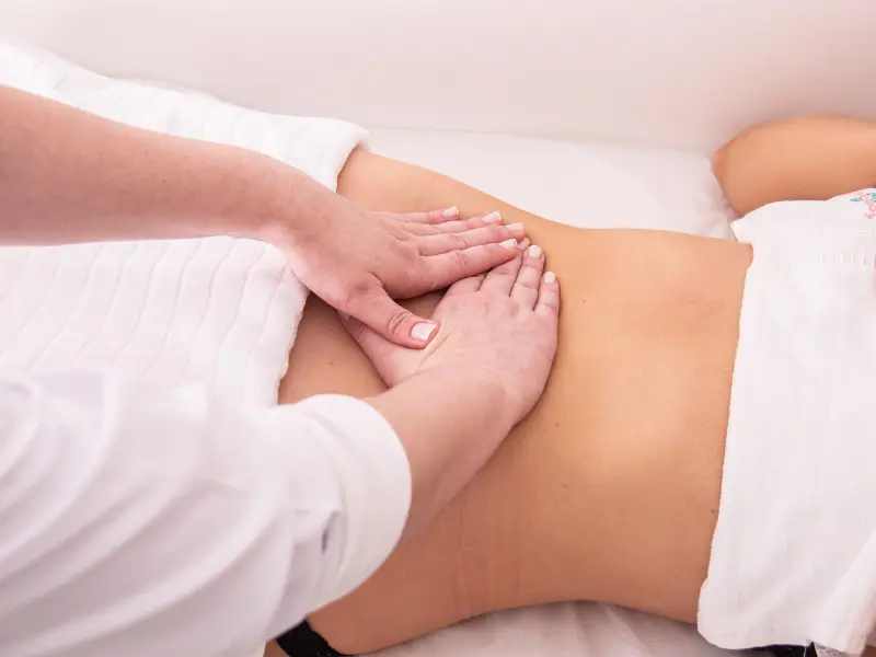 A therapist working with flat palms along the waist during a lymphatic massage